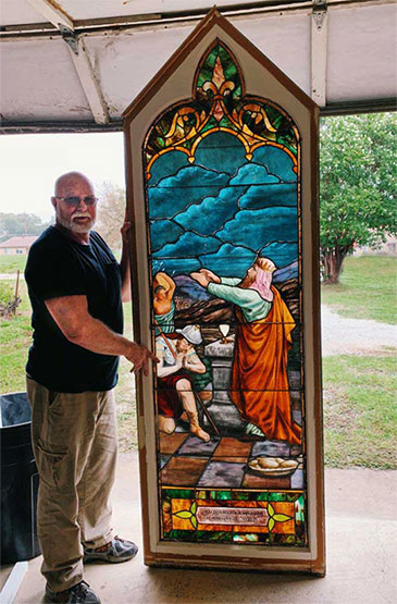 Terry Sewell standing with custom stained glass panel